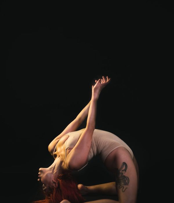 Woman performing a gentle yoga stretch in a dark room.